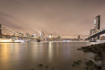 River by illuminated buildings against sky at night