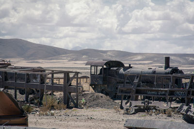 Abandoned train on field against sky