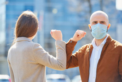 Man and woman wearing mask bumping elbow