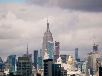 Modern buildings in city against cloudy sky