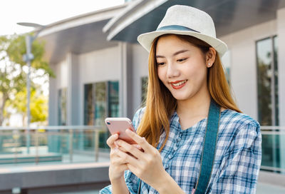 Beautiful young woman using mobile phone outdoors