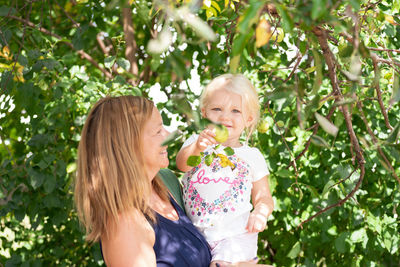 Mother and daughter picking fruits under plants