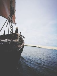 Low section of person on boat moored at sea against sky