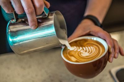 Close-up of hand holding coffee cup on table