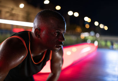 Sweaty ethnic athlete resting at night