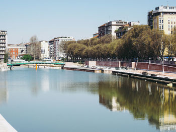 Bridge over river by buildings against sky