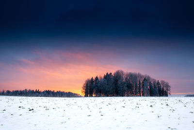 Scenic view of snow covered land against sky at sunset