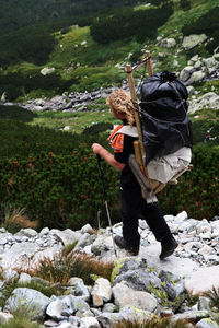 Rear view of woman standing on rock by river