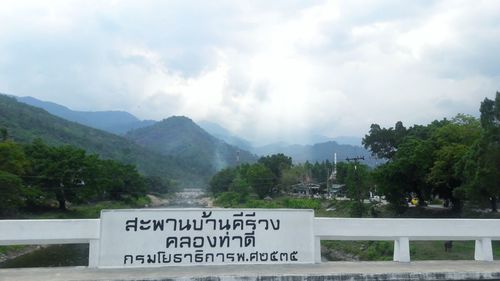 Information sign on mountain against cloudy sky