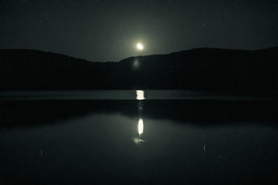 Scenic view of lake against sky at night