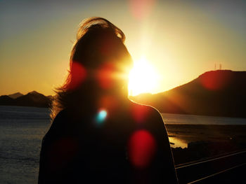 Rear view of silhouette woman against sky during sunset