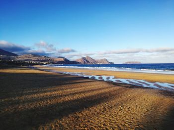 Scenic view of beach against blue sky