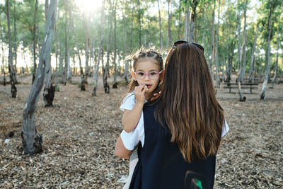 Rear view of mother with daughter standing on land