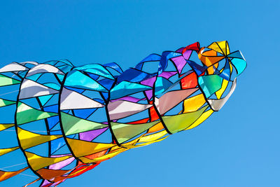 Low angle view of rainbow kite against clear blue sky