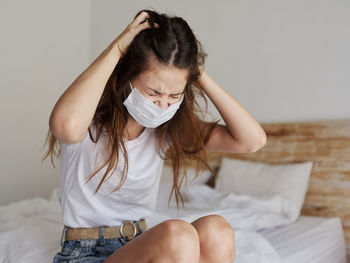 Midsection of woman sitting on bed at home