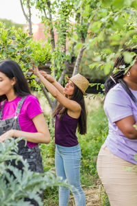 Side view of friends standing against plants