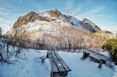 Snow covered bench against sky