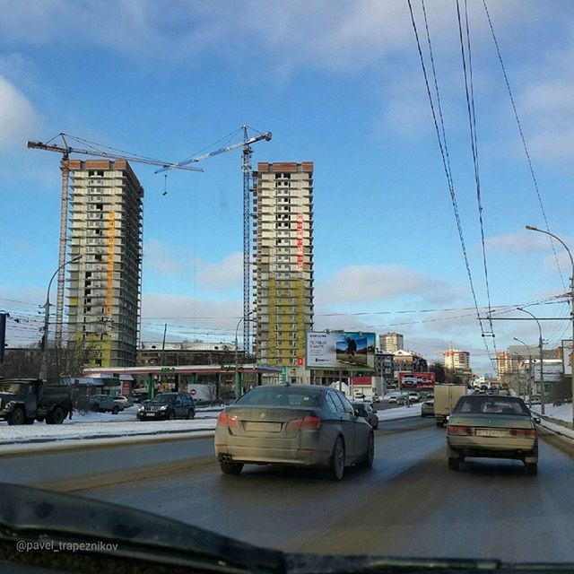 building exterior, transportation, architecture, built structure, sky, crane - construction machinery, mode of transport, city, car, development, land vehicle, street, construction site, crane, cloud - sky, road, cloud, low angle view, outdoors, street light