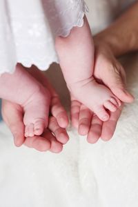 Cropped hands of parent holding baby barefoot