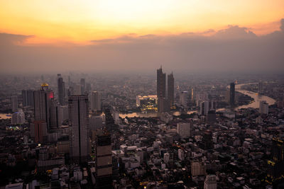 Aerial view of buildings in city at sunset