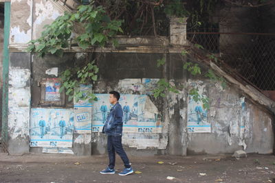 Full length of man standing against graffiti wall