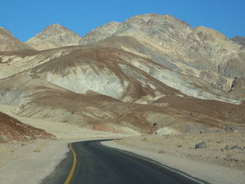 Scenic view of desert road against clear sky