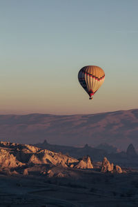 Hot air balloon flying over rocks against sky