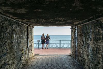 Rear view of people on railing by sea