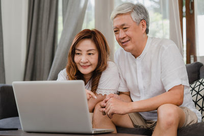 Happy woman using phone while sitting on laptop