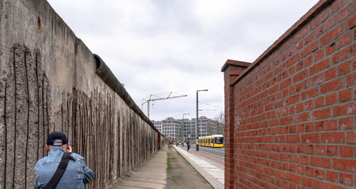 Rear view of man standing by wall against sky