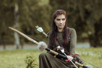 Beautiful archer holding bow and arrow while standing outdoors