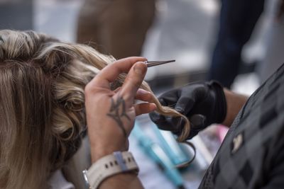Cropped hands of hairdresser by woman in salon