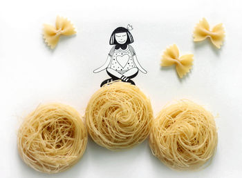 Close-up of raw yellow pasta and illustration of a girl sitting on it like on hay ball