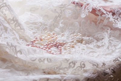 Close-up of pearl jewelry on lace fabric