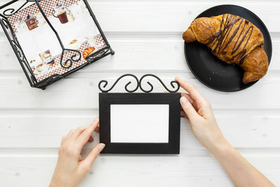 Low section of woman holding smart phone on table