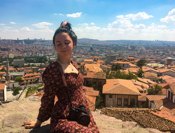 Young woman against buildings in city against sky