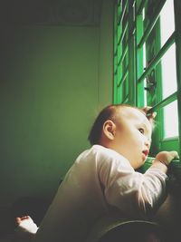 Baby boy looking though window at home