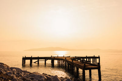 Pier over sea against sky during sunset