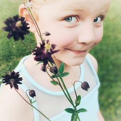 Close-up portrait of cute girl against white flowering plants