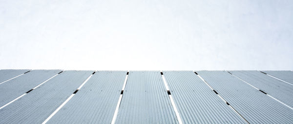 Low angle view of electricity pylon on roof against sky