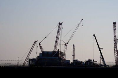 Cranes at construction site against clear sky