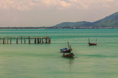 Fishing boats in sea against sky