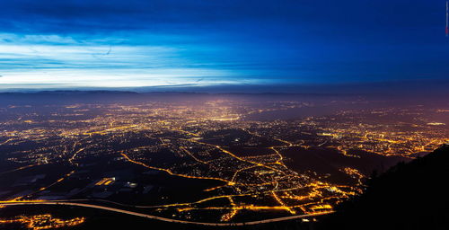 Aerial view of illuminated cityscape against sky at night