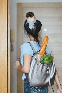 Rear view of woman with food in backpack at home