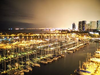 Panoramic view of illuminated city by sea against sky