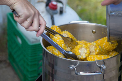 Midsection of person preparing food, corn boil