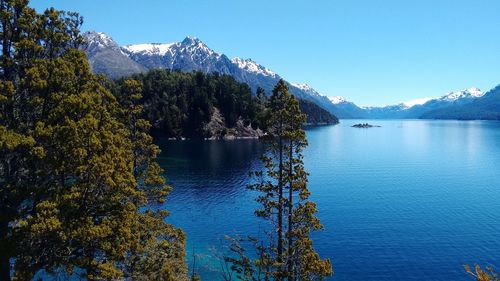 Scenic view of lake and mountains against clear blue sky