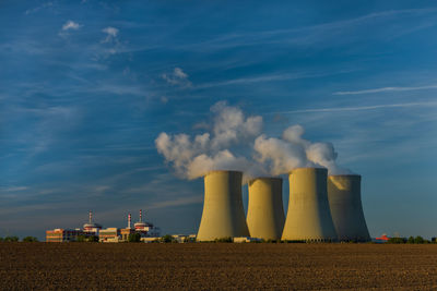 Smoke emitting from factory against sky