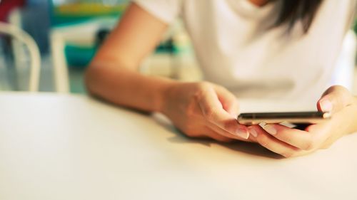 Midsection of woman using mobile phone on table