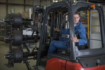 Factory working driving a fork lift in warehouse